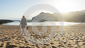 Curvy blond hair girl relaxing alone, barefoot walking in a tropical beach shore with a summer dress in a empty beach on the