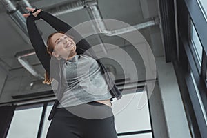 Curvy girl in gym stretching