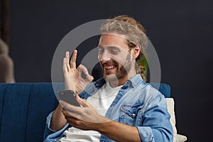 Curvy guy using smartphone and smiling. Happy man using mobile phone apps, texting message, browsing internet, looking