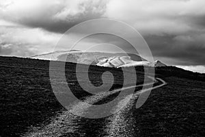 A curvy mountain road beneath a cloudy sky