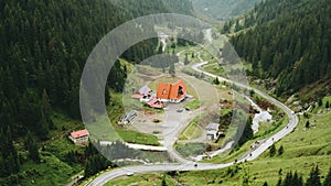 Curvy mountain road through green forest valley with trees, villages and rainy fog