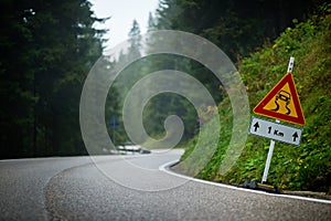 Curvy mountain road with slippery route sign