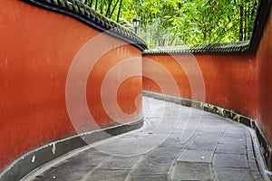 Curvy red walls passage surrounded by bamboo forest.