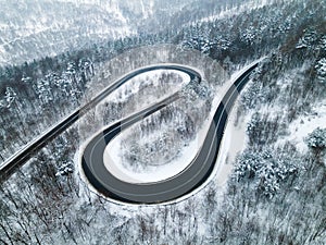 Curvy Windy Road in Snow Covered Forest, Top Down Aerial Drone View