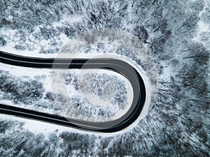 Curvy Windy Road in Snow Covered Forest, Top Down Aerial Drone View