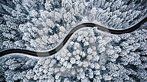 Curvy windy road in snow covered forest, top down aerial view