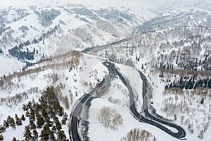Curvy windy road in snow covered mountain hill. Top down aerial view. Scenic winter background captured from above