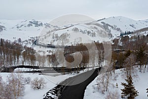 Curvy windy road in snow covered mountain hill. Top down aerial view. Scenic winter background captured from above
