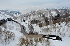 Curvy windy road in snow covered mountain hill. Top down aerial view. Scenic winter background captured from above