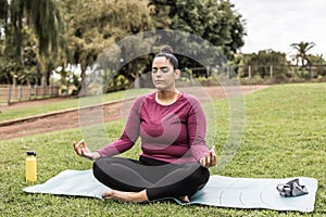 Curvy woman doing yoga session outdoor at city park - Focus on face