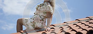 Curvy Woman Posing on Red-Tiled Roof Under Summer Sky