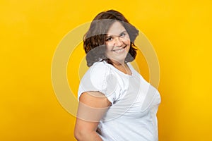 Curvy young woman smiling on a yellow background