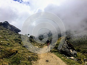 A young group of international hikers, led by their local Inca guide, navigate the Andes mountains through the clouds