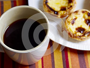 Custard tarts in a plate softfocus and black coffee cup