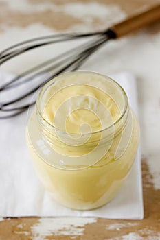 Custard vanilla cream in a glass jar on a wooden background.