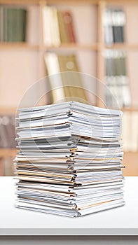 Stack of documents on a white table in a light-filled office setting