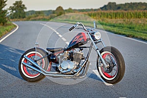 Custom bobber motorbike standing on a road.