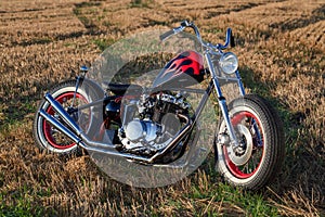 Custom bobber motorbike standing in a wheat field.