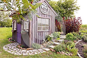 Custom Built Cottage Like Garden Shed with Cobblestone Sidewalk and Wood Board and Batten Siding photo