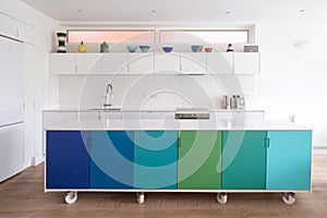 Custom designed kitchen island in open plan kitchen on industrial castor wheels, retro design painted in blue and green colours.