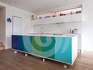 Custom designed kitchen island in open plan kitchen on industrial castor wheels, retro design painted in blue and green colours.