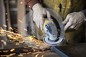 Custom furniture worker grinds weld seam on steel frame.