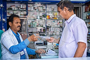 Customer asking medicine to pharmacist by showing doctor proscription at pharma retail store - concept of small business