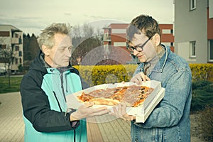 Customer assuming a pizza food from a delivery man on sidewalk photo