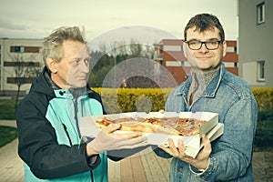 Customer assuming a pizza food from a delivery man on sidewalk photo