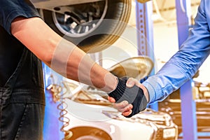 Customer and auto service mechanic shake hands. Car repair and maintenance