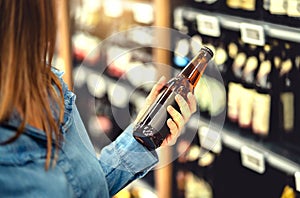 Customer buying beer in liquor store. Lager, craft or wheat beer. IPA or pale ale. Woman at alcohol shelf. photo