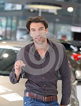 Customer in the car dealership holds the car key of the newly pu
