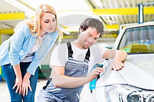 Customer and car painter in auto workshop