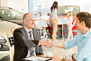 Customer and car salesman shaking hands photo