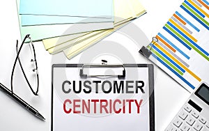 CUSTOMER CENTRICITY text on paper sheet with chart,color paper and calculator