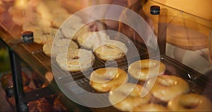 Customer, choice and buy donuts in bakery in closeup, hands and select danish by glass counter. Junk food, cake and