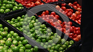 The customer chooses fresh vegetables from the grocery counter in the store. Young man takes a green tomato from a