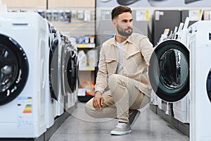Customer choosing washing machine in electronics store