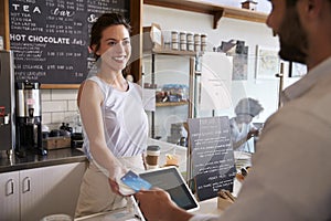 Customer at coffee shop pays smiling waitress with card