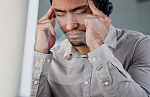 This customer is driving me crazy. a handsome young customer service agent sitting alone in the office and suffering