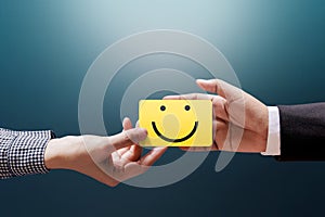 Customer Experience Concept, Happy Client Woman giving a Feedback with Happy Smiley Face Card into a Hand of Businessman photo