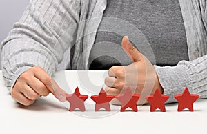 Customer experience feedback concept. Five red stars, the best rating of excellent services with a female hand to meet. White