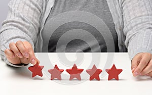 Customer experience feedback concept. Five red stars, the best rating of excellent services with a female hand to meet. White