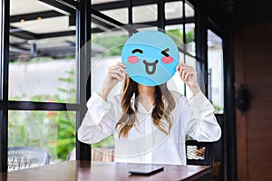 Customer experience review and feedback satisfaction service concept. Woman holding happy face emoji for giving good feedback