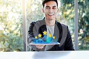 Customer Experiences Concept. Happy Young Man Sitting at the Desk and presenting his Five Star Rating in Online Survey