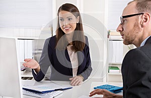 Customer and female financial agent in a discussion at desk.