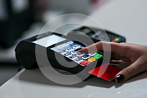 Customer female hand is entering personal identification number pin using payment terminal keypad in shop or supermarket