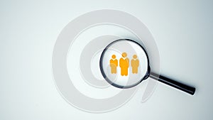 Customer group icons in a magnifying glass placed on a white background represent the selection of business goals, target