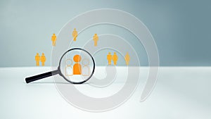 Customer group icons in a magnifying glass placed on a white background represent the selection of business goals, target