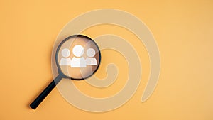 Customer group icons in a magnifying glass placed on a yellow background represent the selection of business goals, target